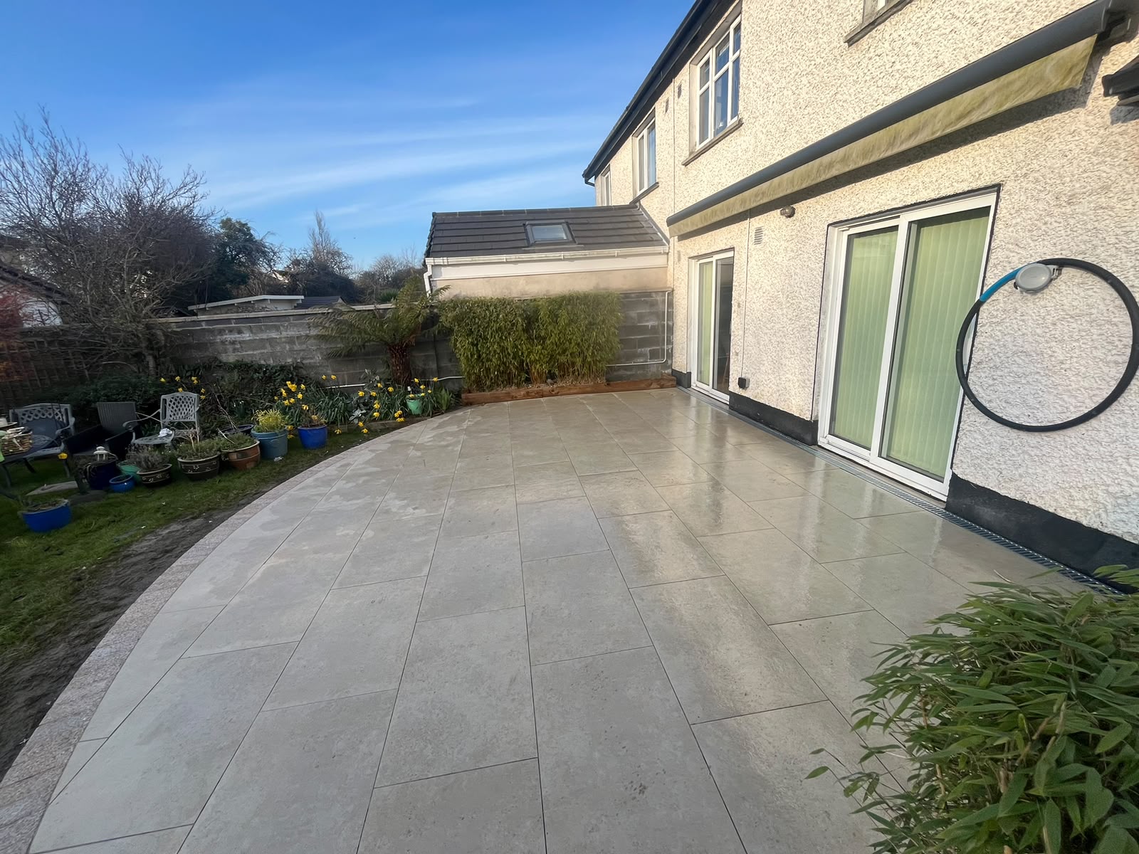 Finished curved porcelain patio with granite border and garden planting
