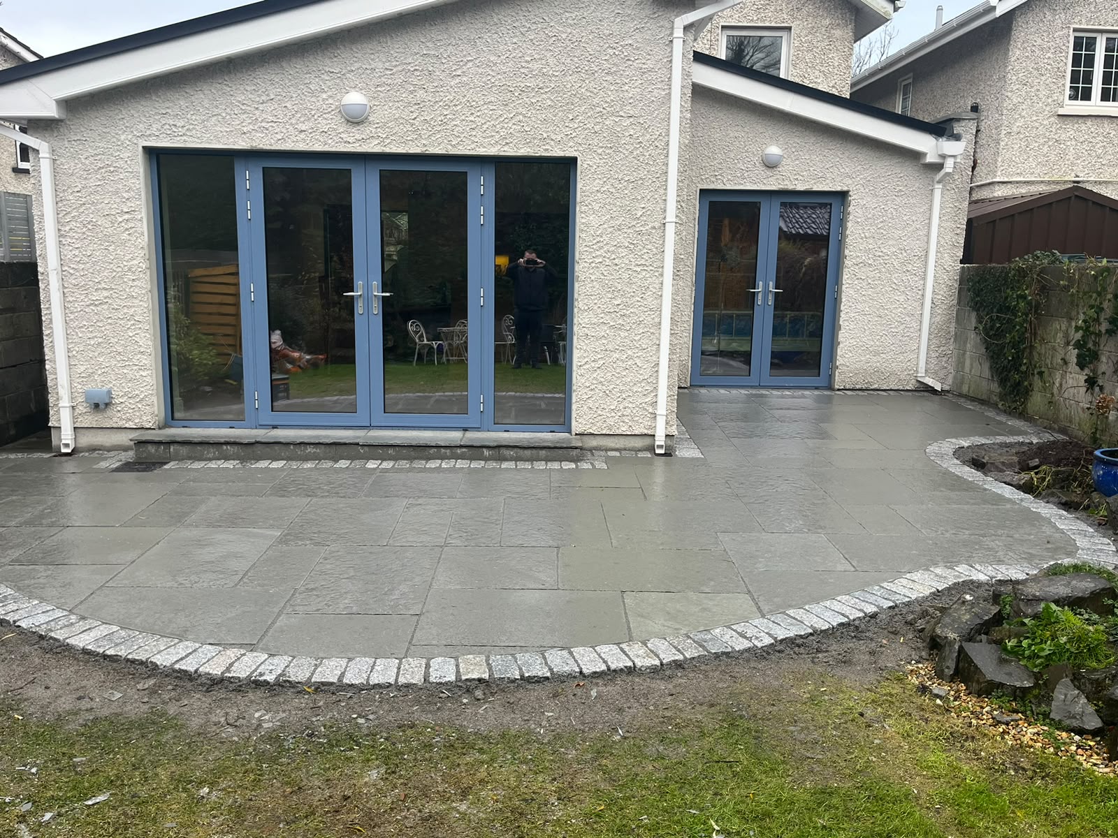 Grey porcelain patio fitted around rear garden doors with curved edging